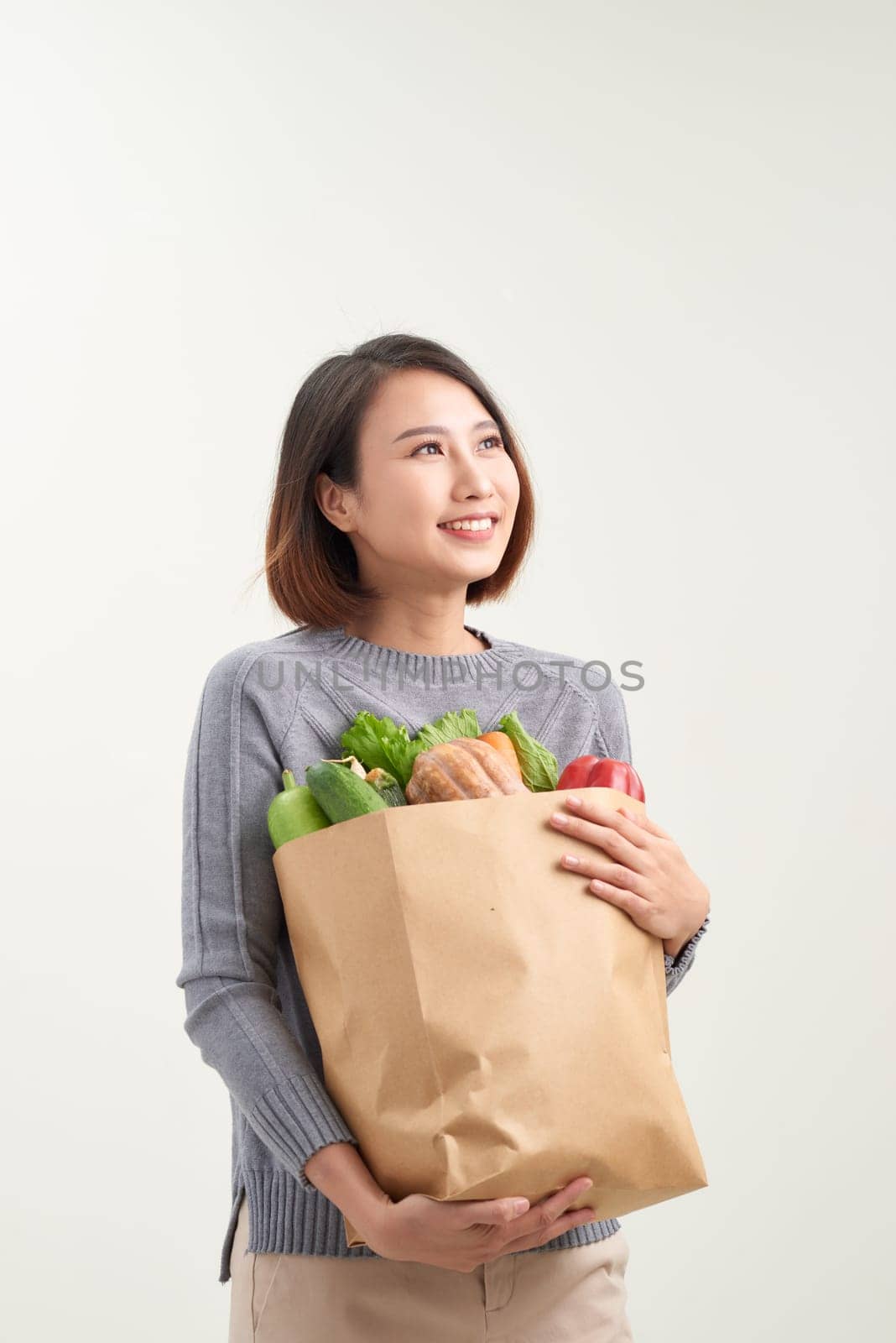 Horizontal orientation color image of a woman holding a paper bag overflowing with vegetables / Adding Veggies to your Diet by makidotvn