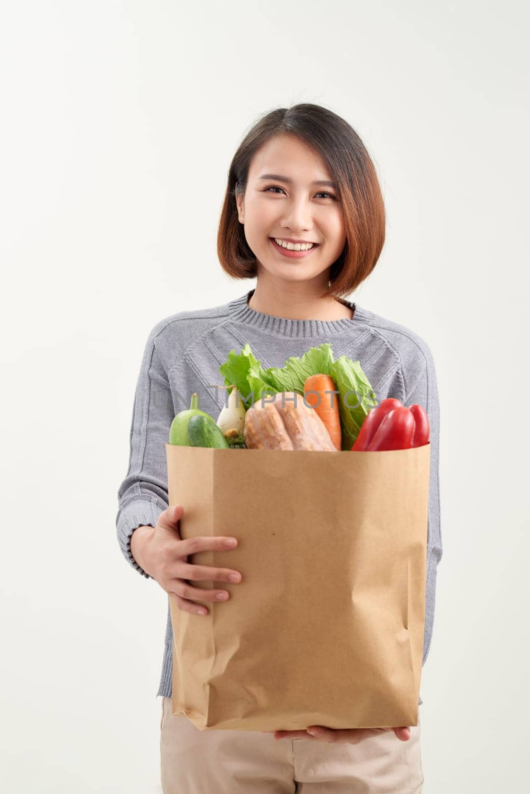 Cheerful woman holding a shopping bag full of groceries