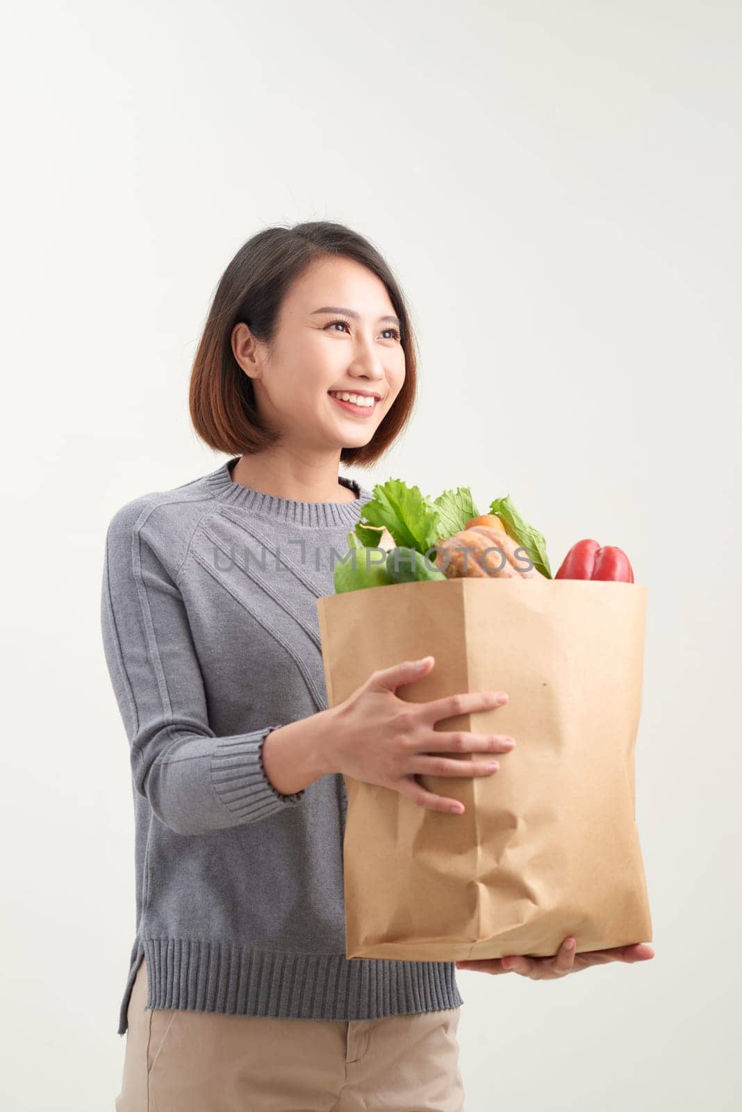 Portrait Of Happy Young Woman Holding Grocery Bag Over White Background by makidotvn