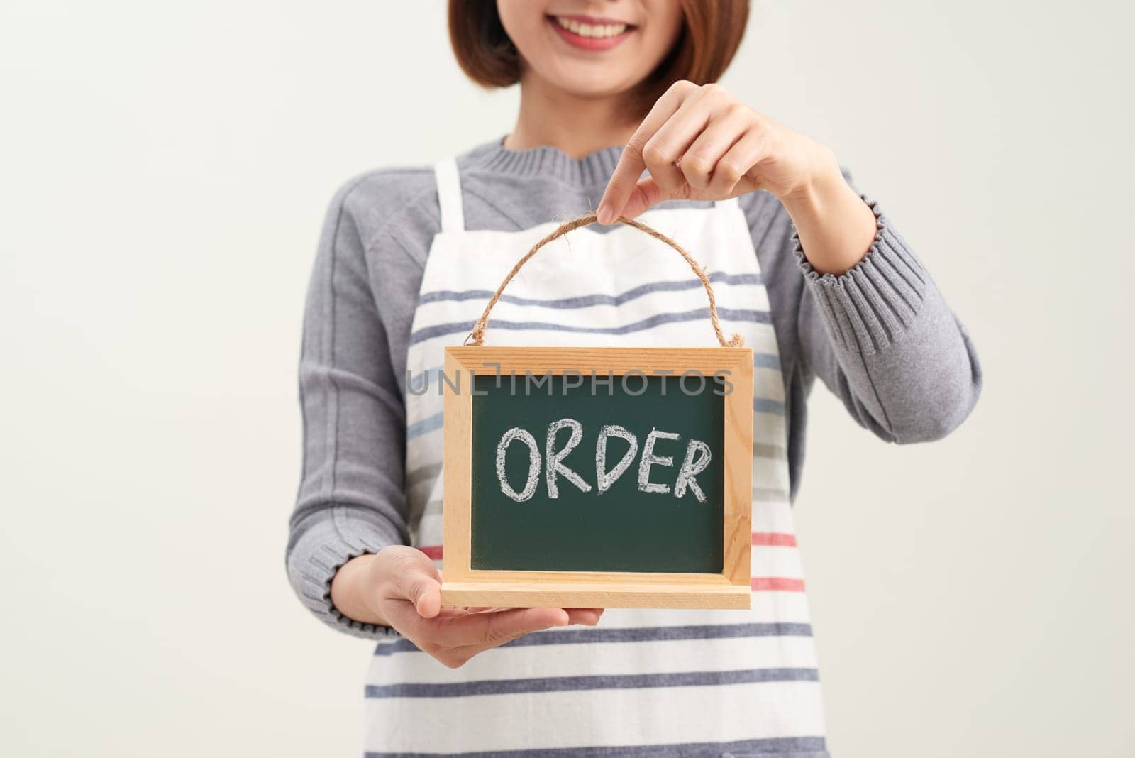 Portrait of smiling waitress showing chalkboard with order sign on white by makidotvn