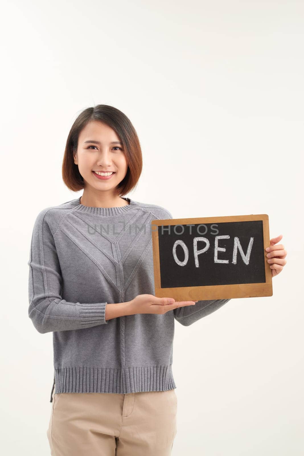 It's open here. A smiling woman is holding a sign with the inscription "open" on a white background isolated. by makidotvn