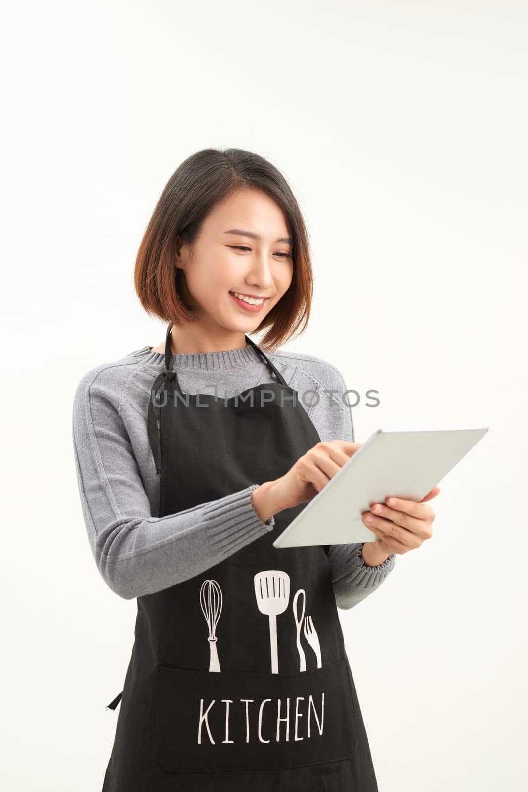 Successful hypermarket employee with black apron holding modern tablet isolated on white background with copyspace by makidotvn