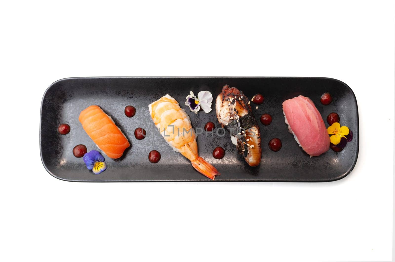 Nigiri sushi set with salmon, eel, tuna and shrimp, flat lay on black plate isolated. Traditional Japanese food, sushi restaurant menu. High quality photo