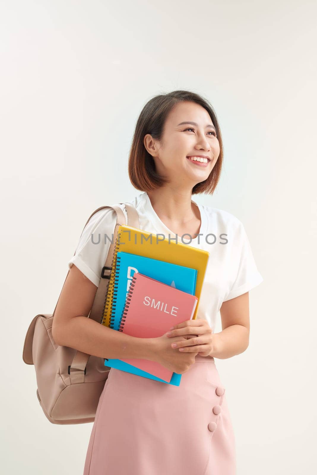 Young asian girl student with backpack hold books isolated on white background studio portrait by makidotvn