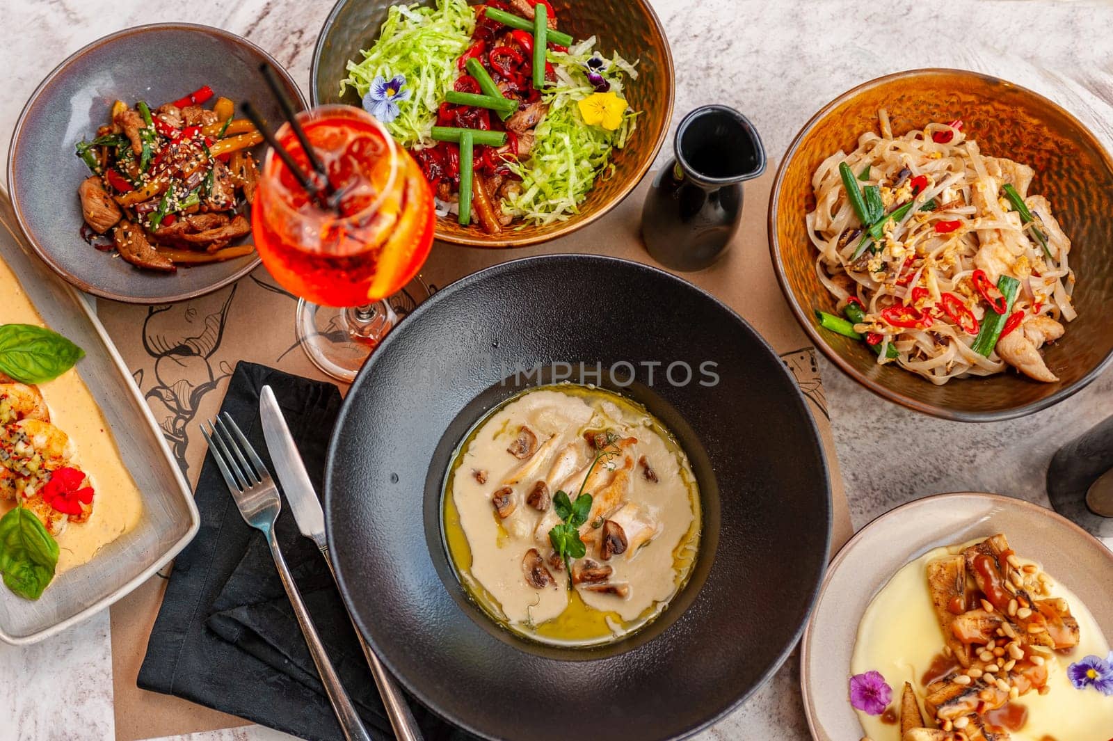 A set of Thai cuisine dishes on a table in a restaurant with a cocktail. View from above. High quality photo