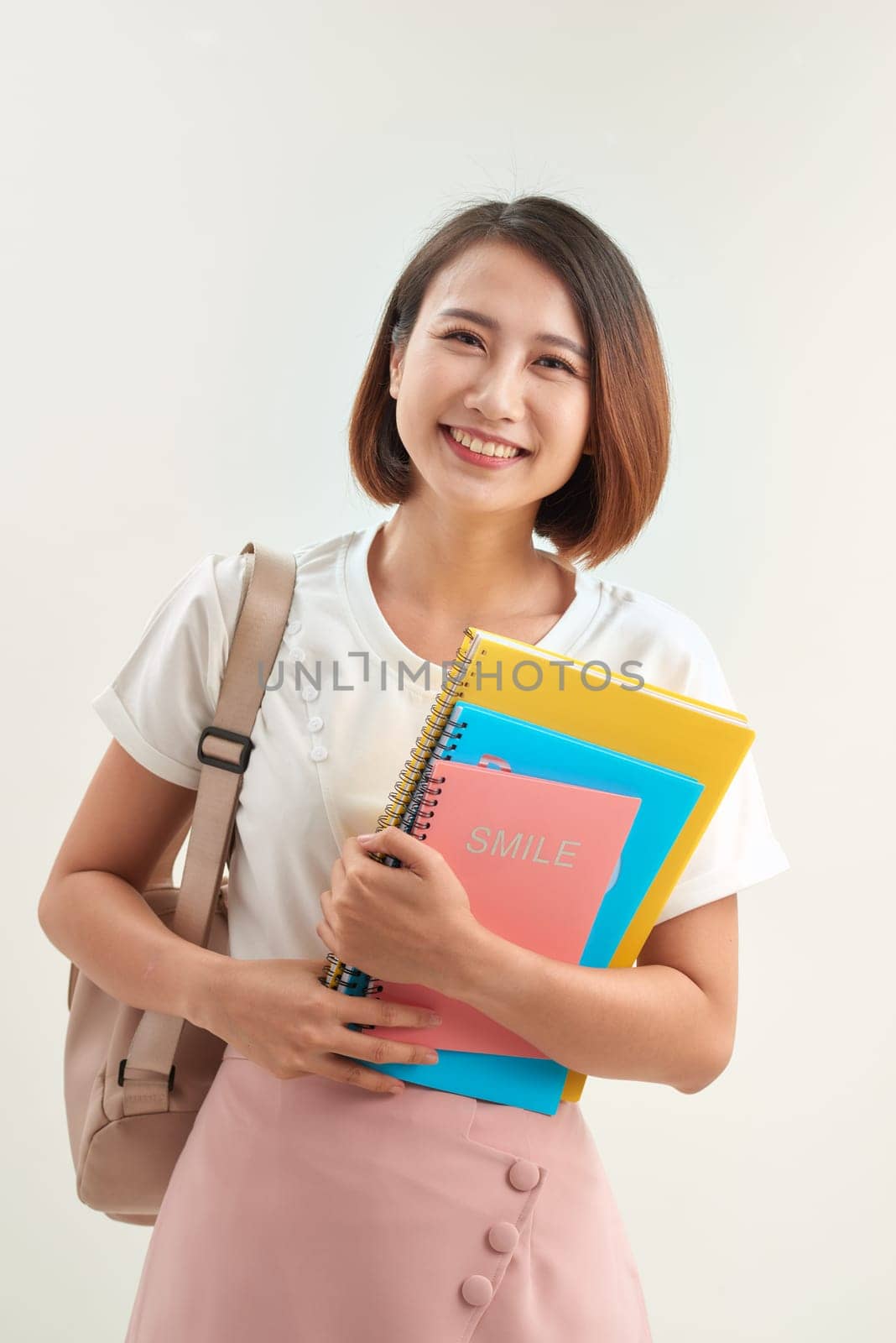 Young woman with books and backpack on white background by makidotvn
