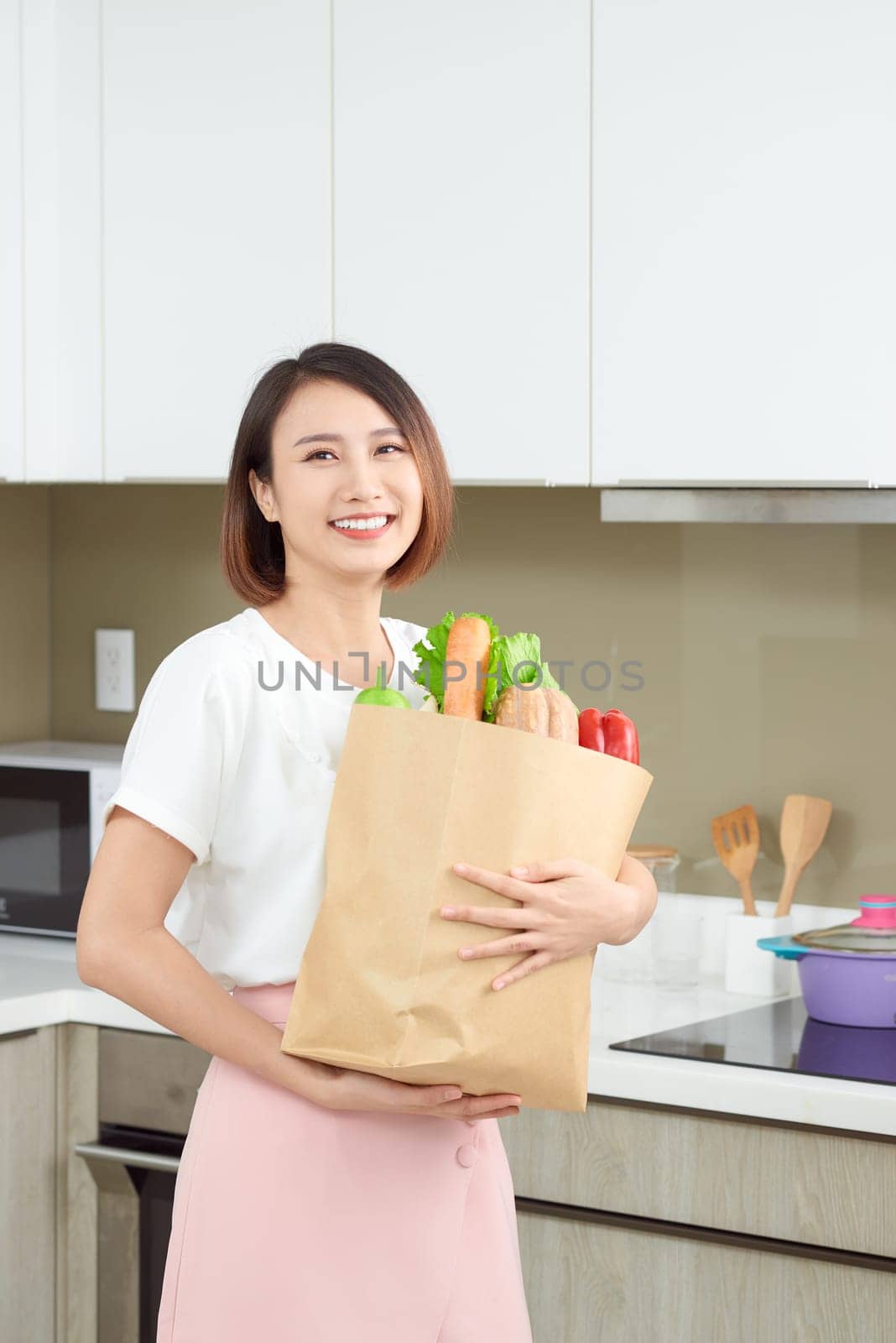 Happy young housewife with shopping bag full of vegetables by makidotvn