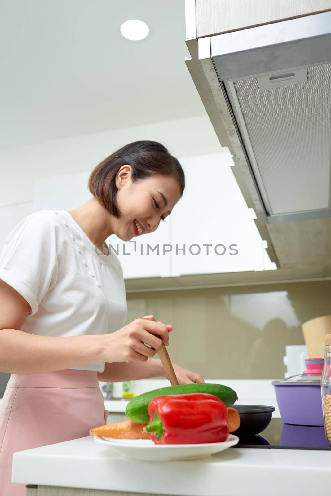 Happy Asian woman cooking in the kitchen. by makidotvn