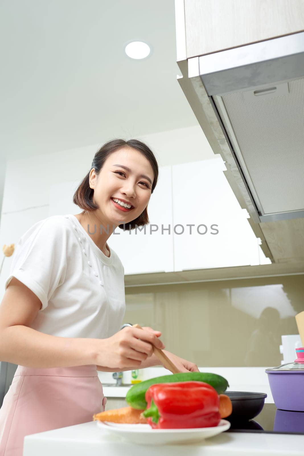Happy Asian woman cooking in the kitchen. by makidotvn