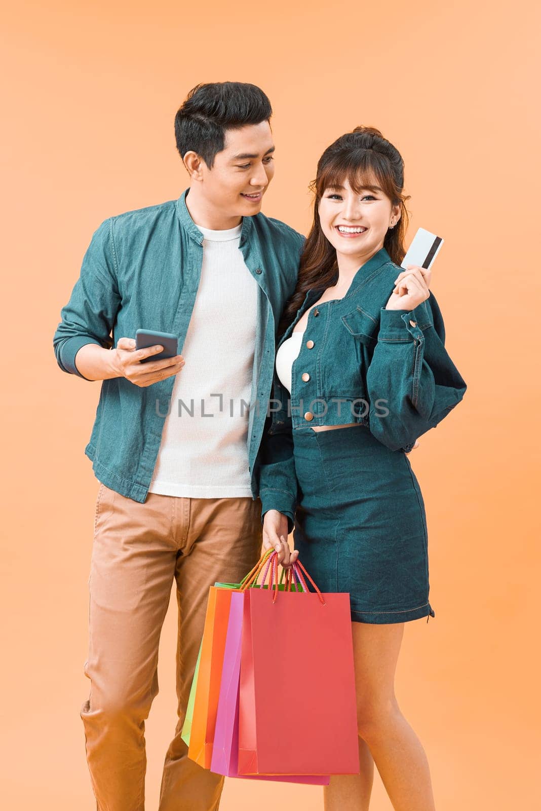 portrait of couple holding shopping bags and credit card isolated 