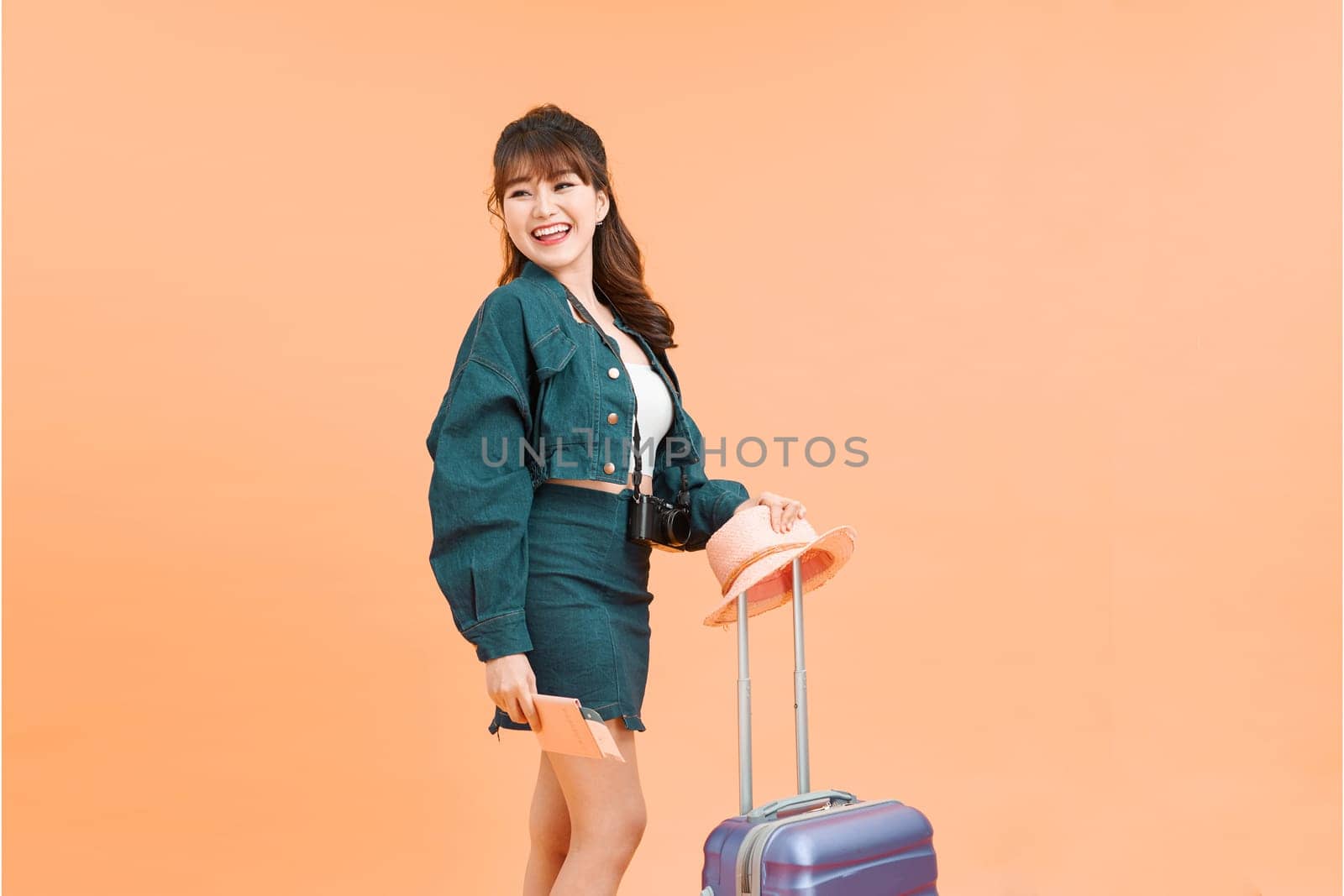 smiling young woman with airplane ticket and bag