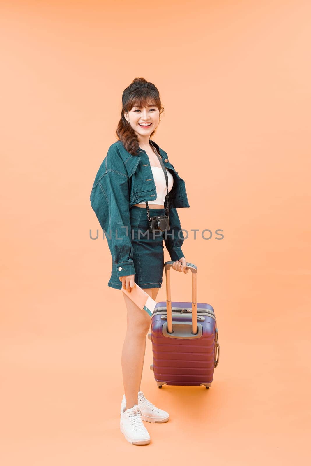 Girl with a suitcase going traveling on color background by makidotvn