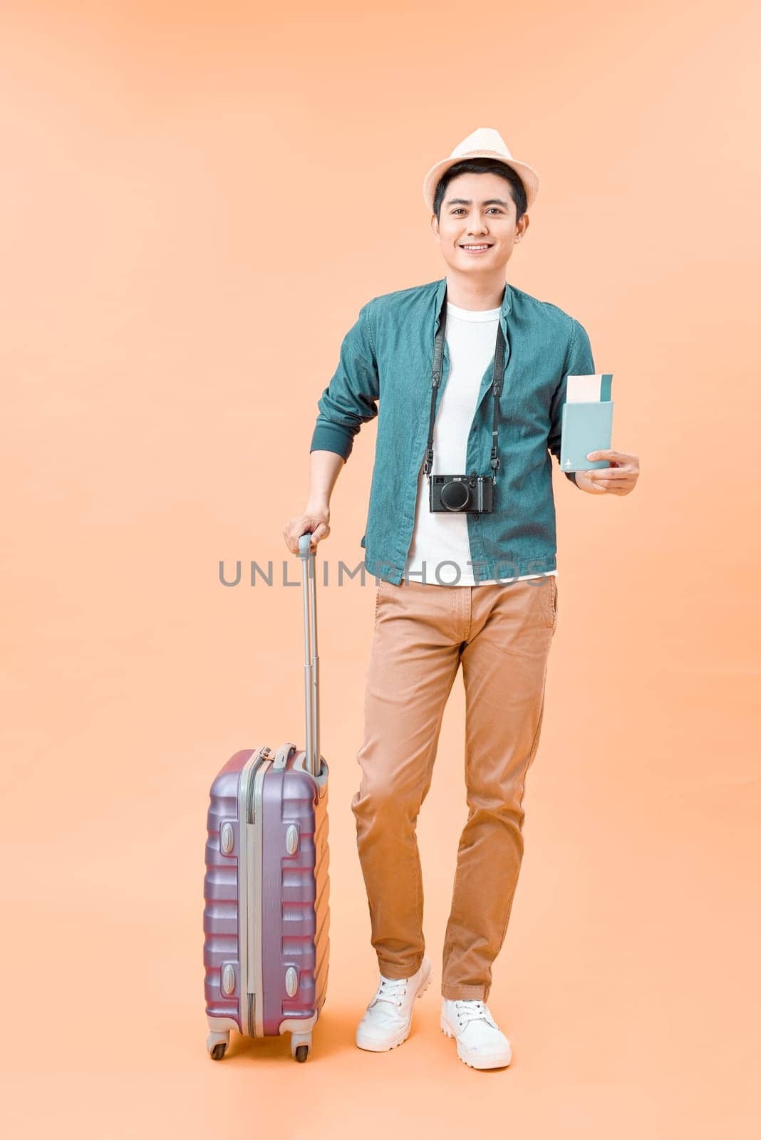 Happy handsome young Asian man with luggage ready to travel for his holidays