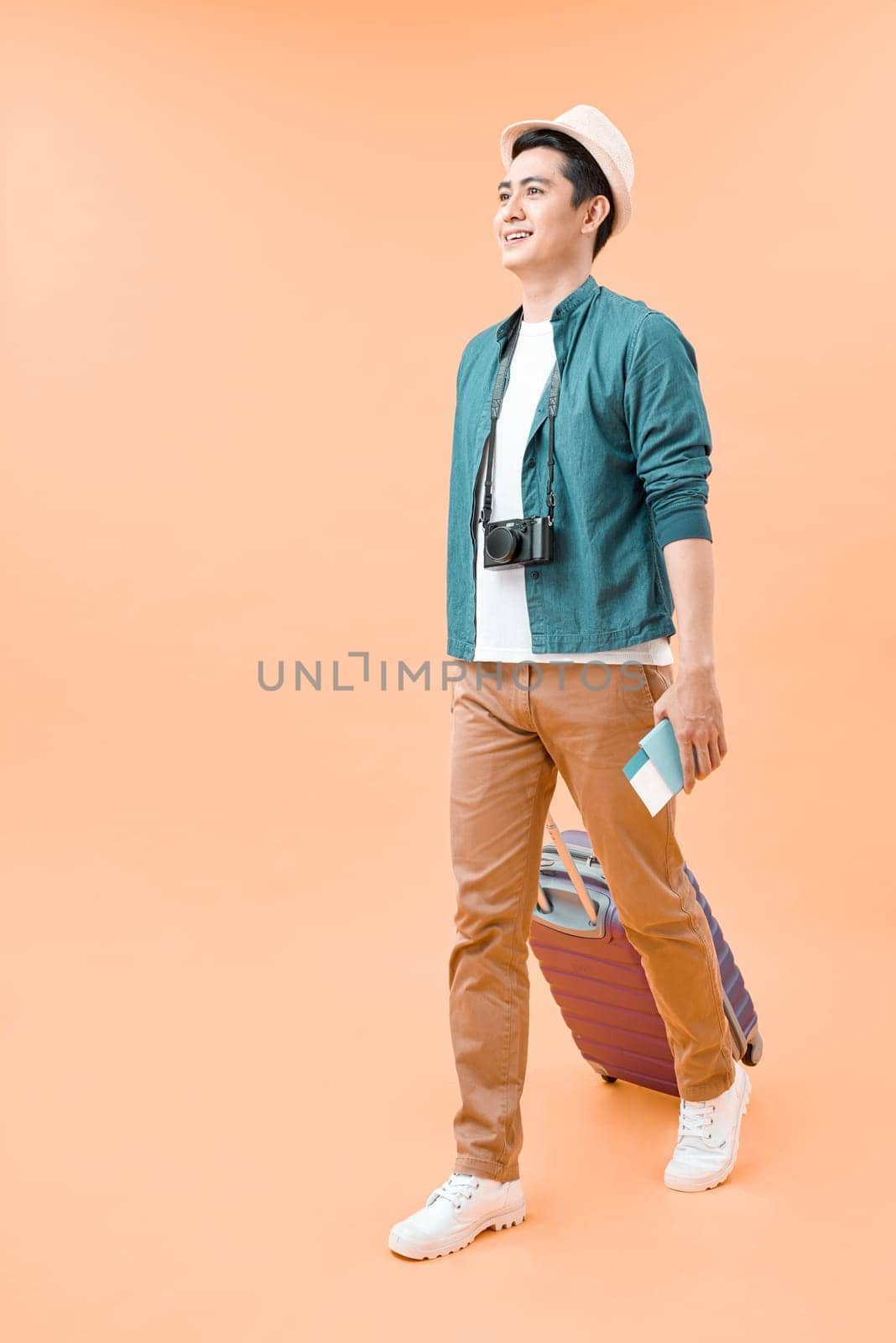 Full length of young asian man walking with the travel bag, isolated on color background by makidotvn