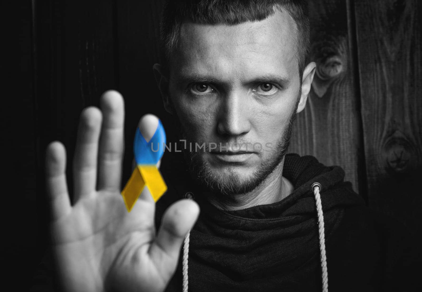 Man holds blue yellow ribbon a symbol of support for ukraine. black and white color. concept needs help and support, truth will win