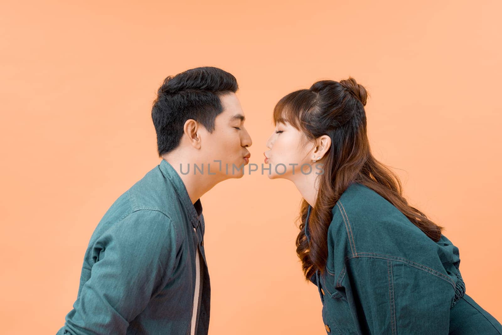Cheerful married spouses kissing closed eyes isolated on beige background