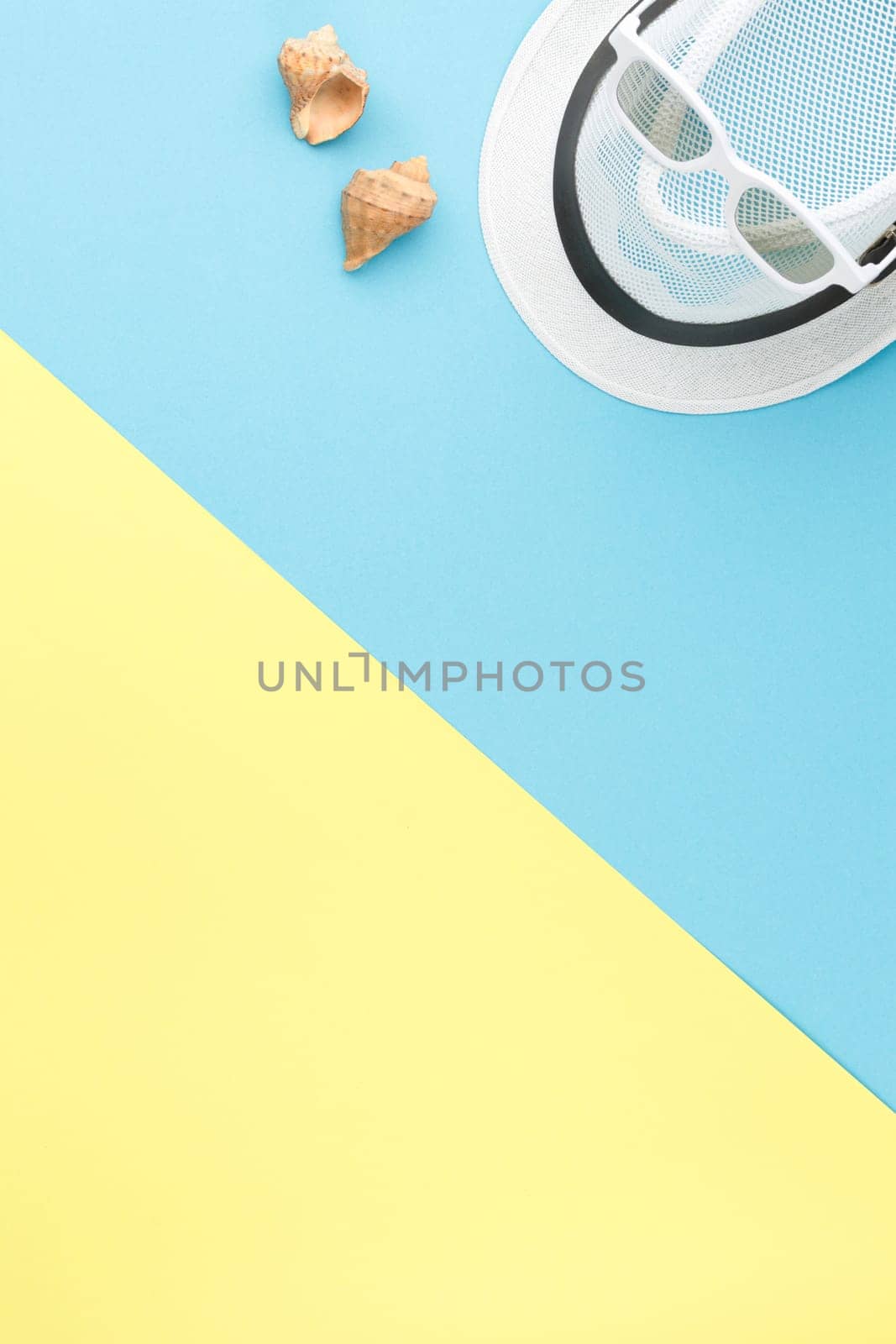 Beach hat with sunglasses and seashells on bicolor isolated background. Top view. Summer vacation concept. Flat lay.