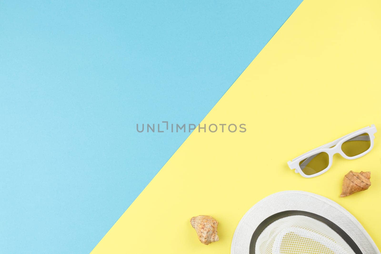 Beach hat with sunglasses and seashells on bicolor isolated background. Top view. Summer vacation concept. Flat lay.