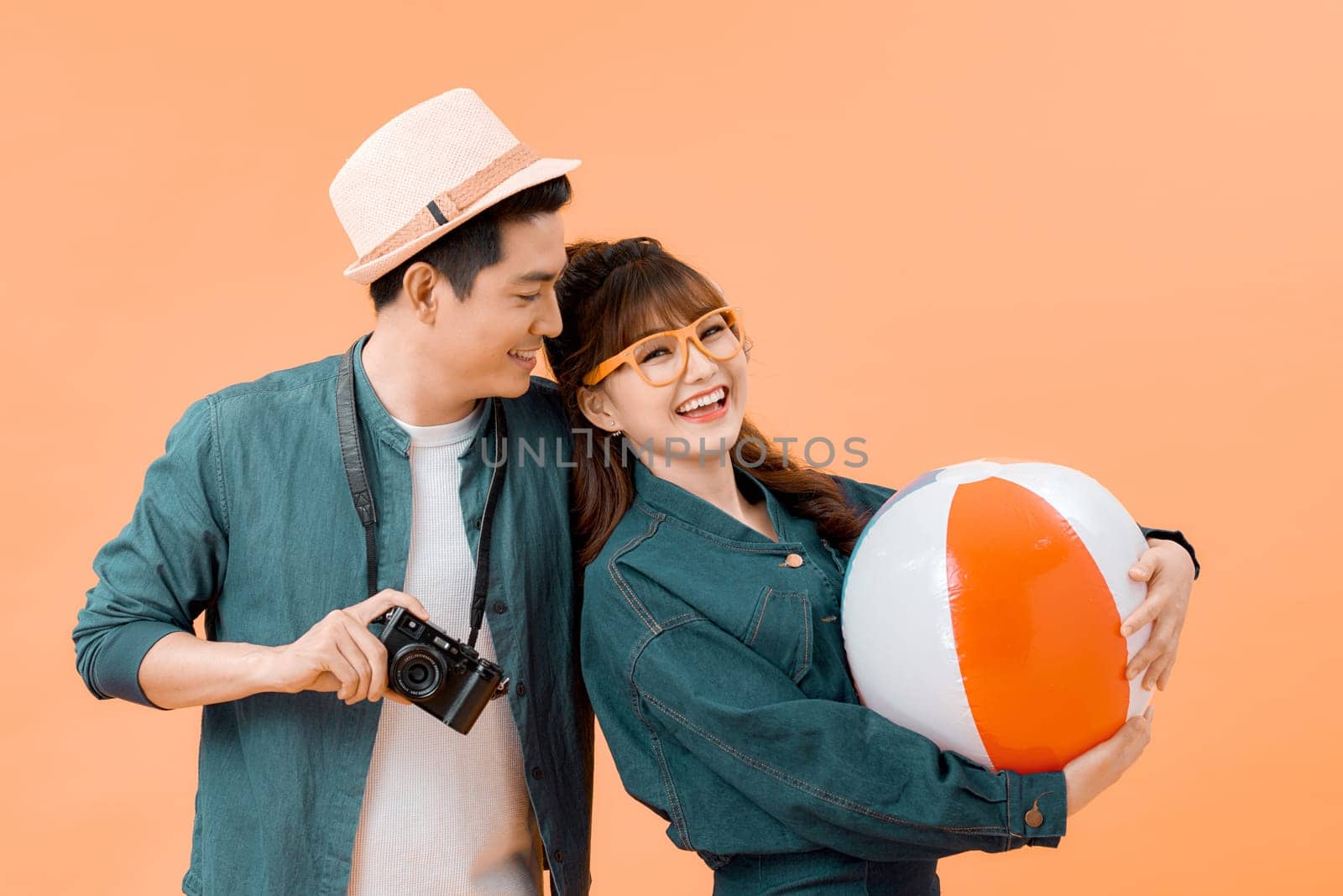 Lovely Asian couple in summer casual clothes and beach accessories studio shot isolated on yellow background by makidotvn