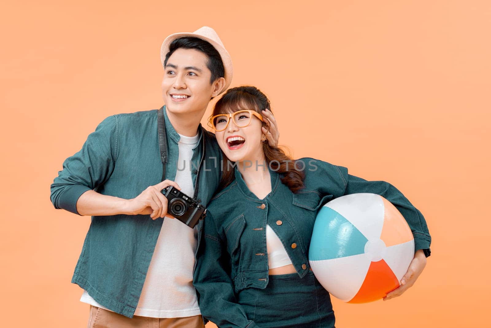 Young couple on a yellow background having fun with a beachball.