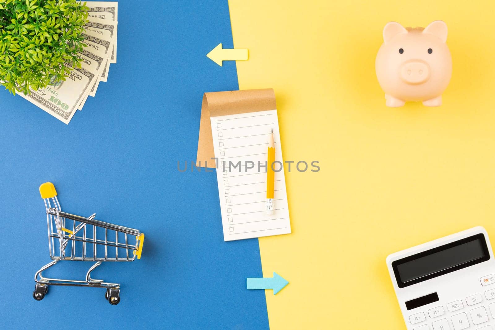 Calculator with notepad on two colored background. Piggy bank with money and supermarket trolley. Top view. Discounts and promotions concept. Flat lay.