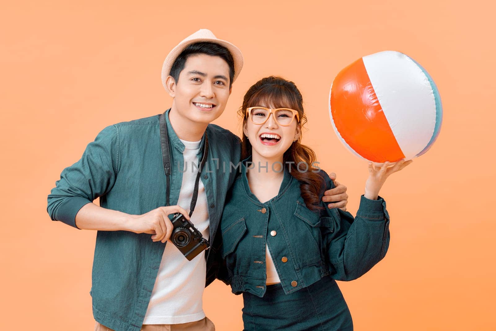 Lovely Asian couple in summer casual clothes and beach accessories studio shot isolated on yellow background