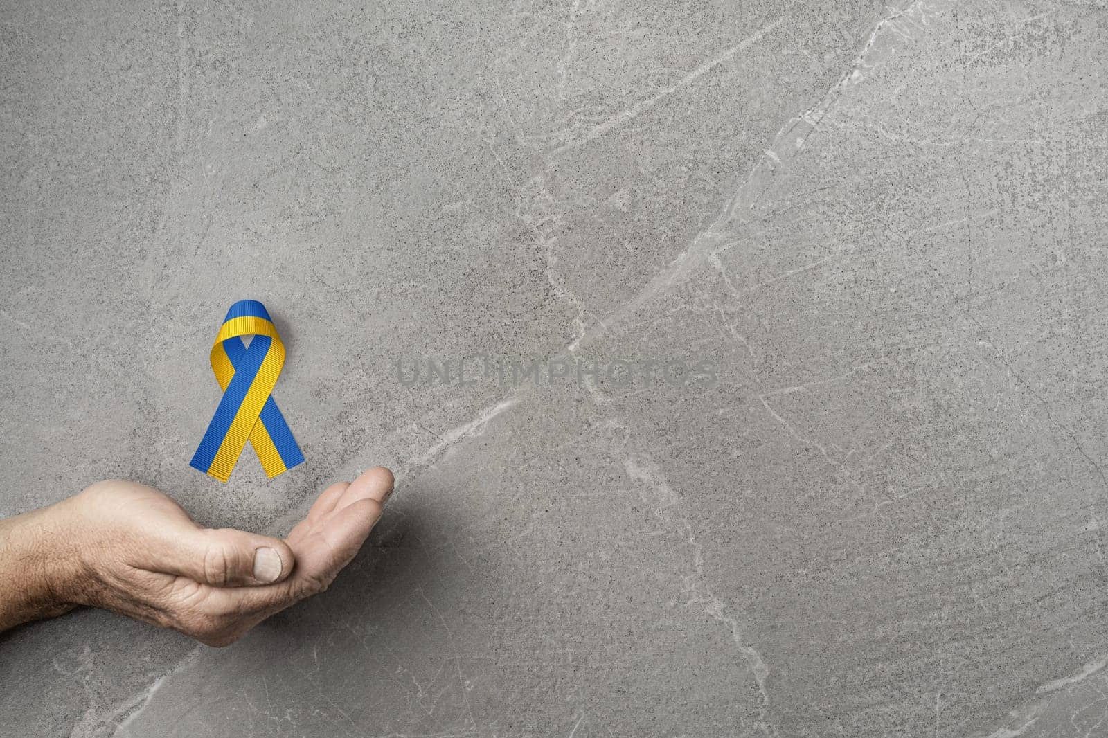 hand with yellow and blue ribbon on marble by alexxndr