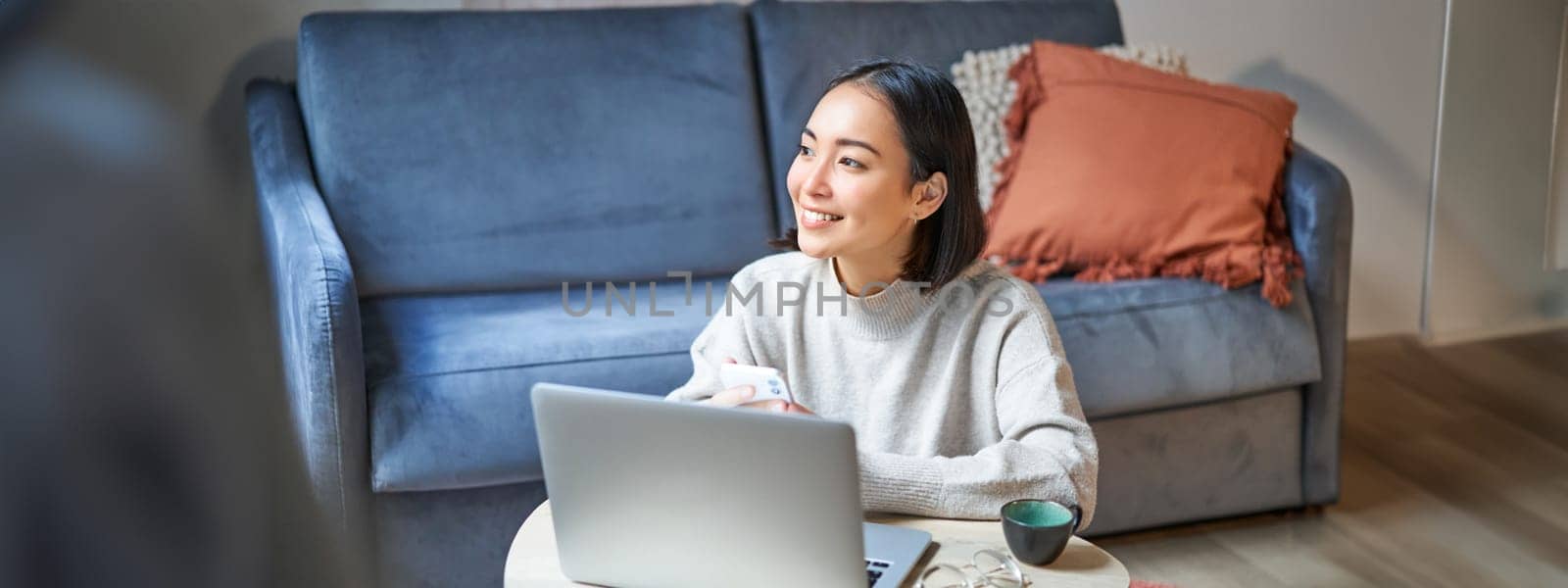 Work from home, freelance and e-learning concept. Young woman studying, sitting in front of laptop, working on remote, worplace in living room by Benzoix