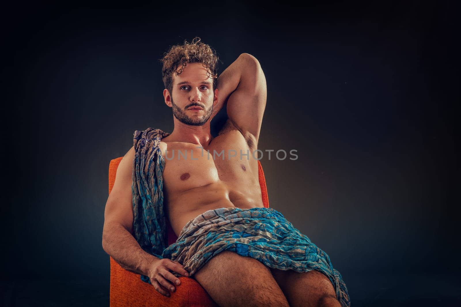 A man with a towel wrapped around his body sitting on a chair
