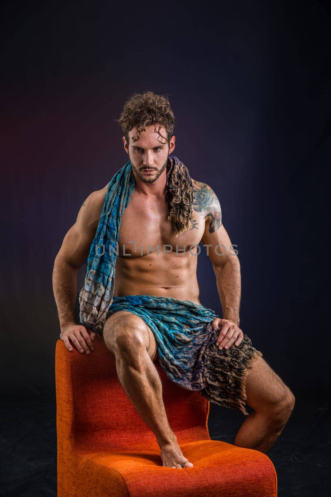 Photo of a shirtless man sitting on an orange chair by artofphoto