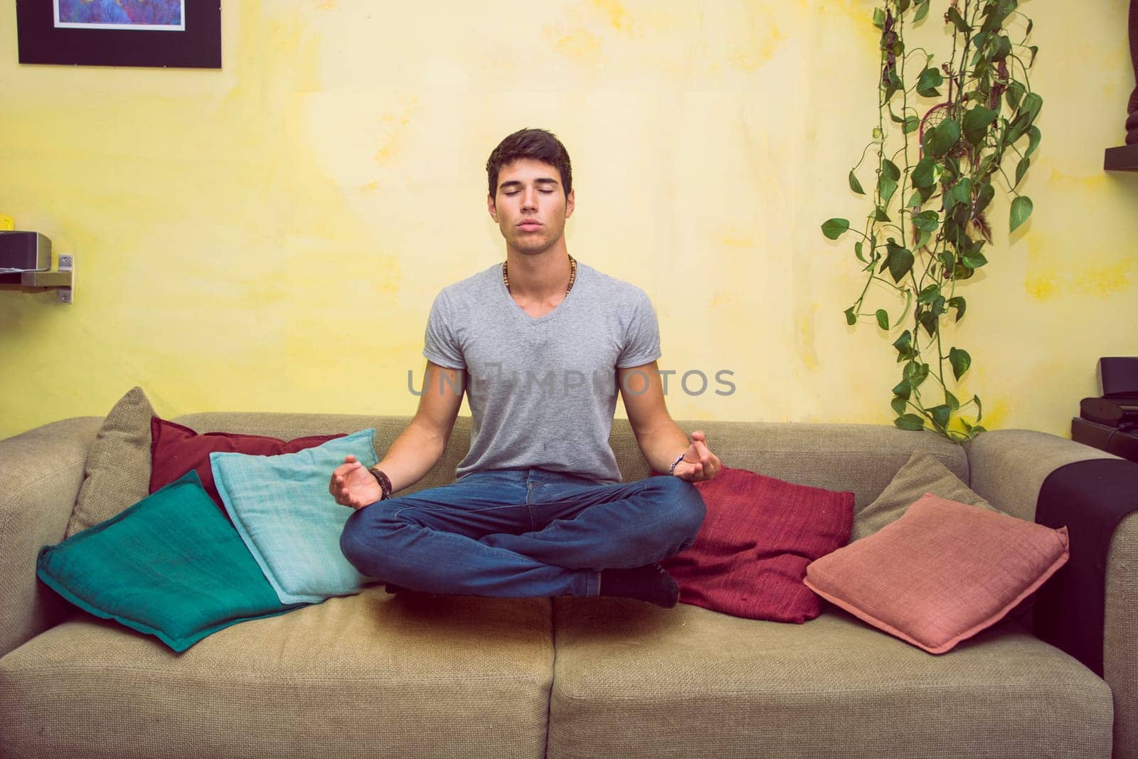 A man sitting on a couch in a yoga pose, magically levitating in the air
