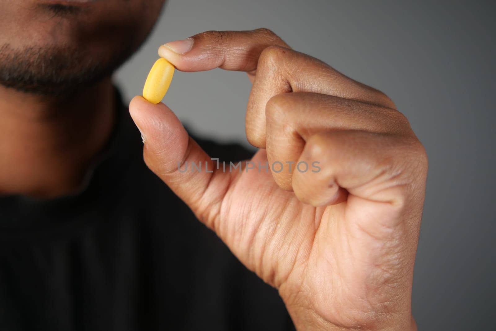 A person holds a yellow capsule, emphasizing the importance of health and wellness