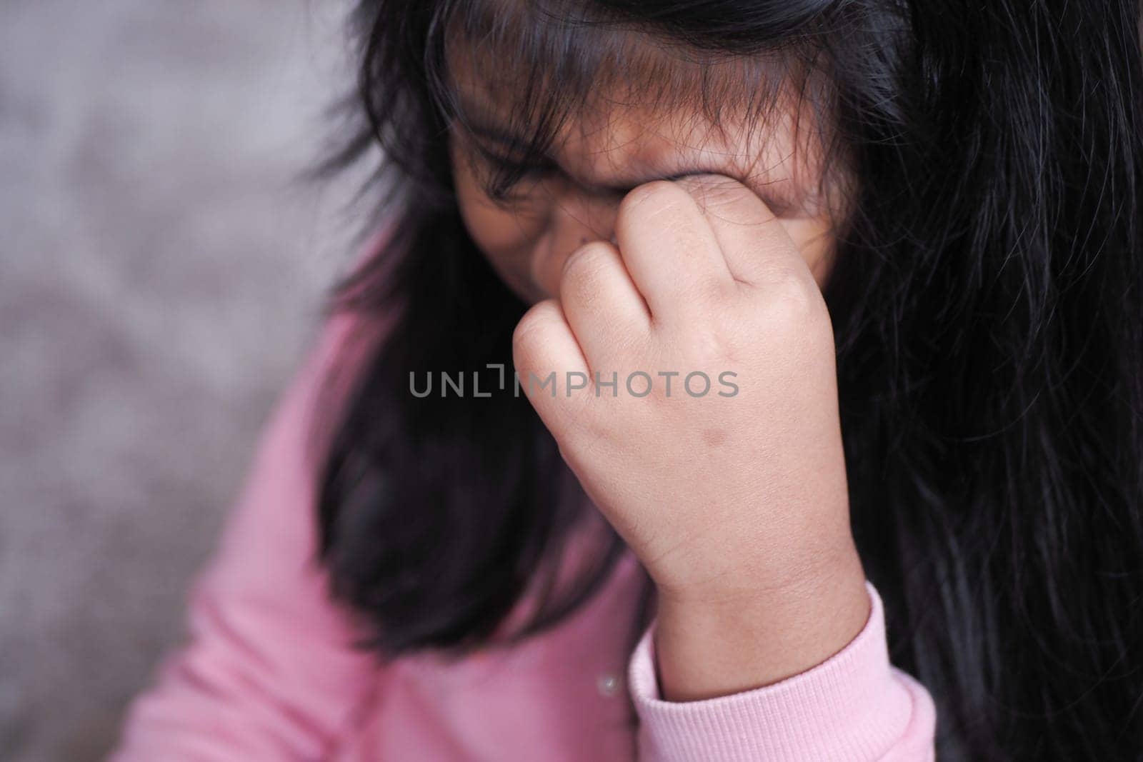 A child gently covers their face with their hands, reflecting profound emotions and deep thoughts