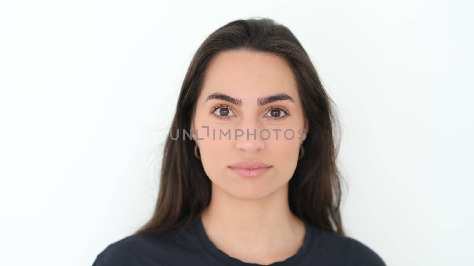 A front portrait of a confident young woman with long hair, showcasing natural beauty and simplicity.