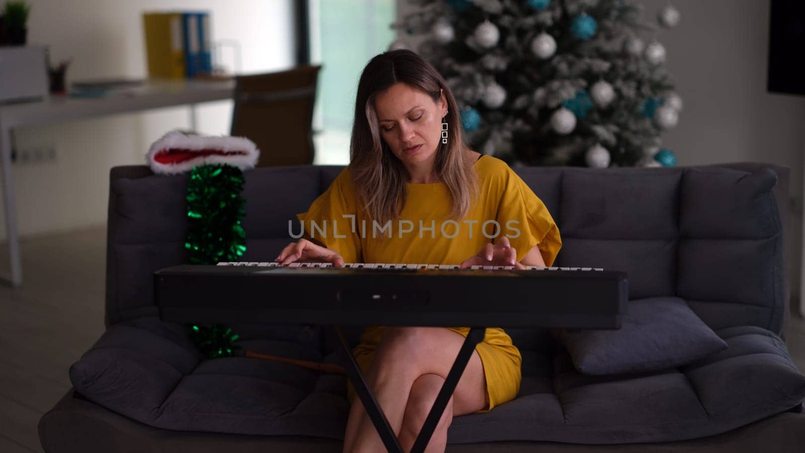 A young woman joyfully enjoys playing a colorful keyboard in a modern, festive holidaythemed living room setting