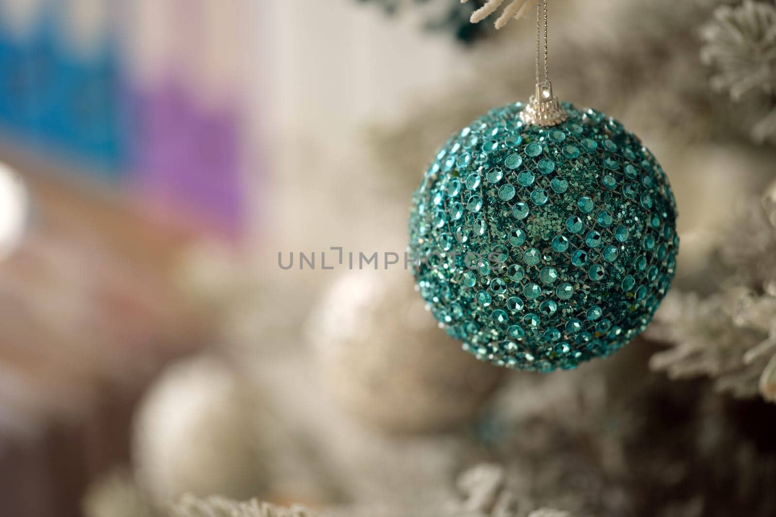 A stunning turquoise ornament, adorned with shimmering and sparkling gems, beautifully hangs on a festive tree