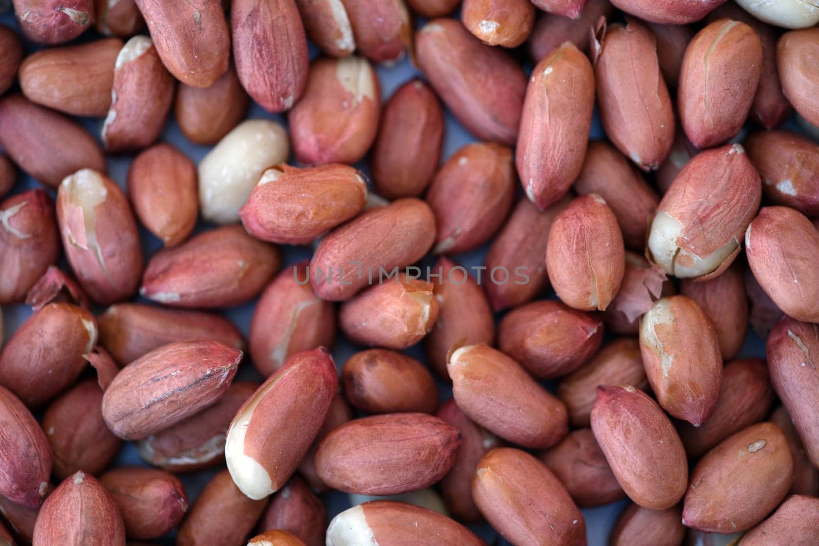 This is a detailed closeup view of raw peanuts that showcases their unique reddishbrown skin texture beautifully