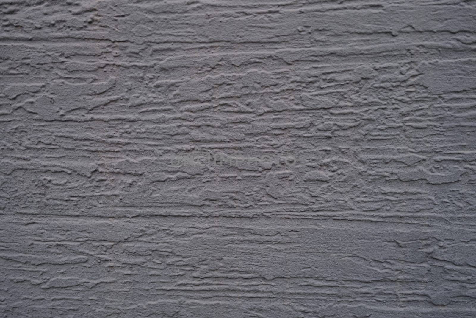 A closeup photograph of a beautifully textured gray wall that showcases intricate patterns and its depth