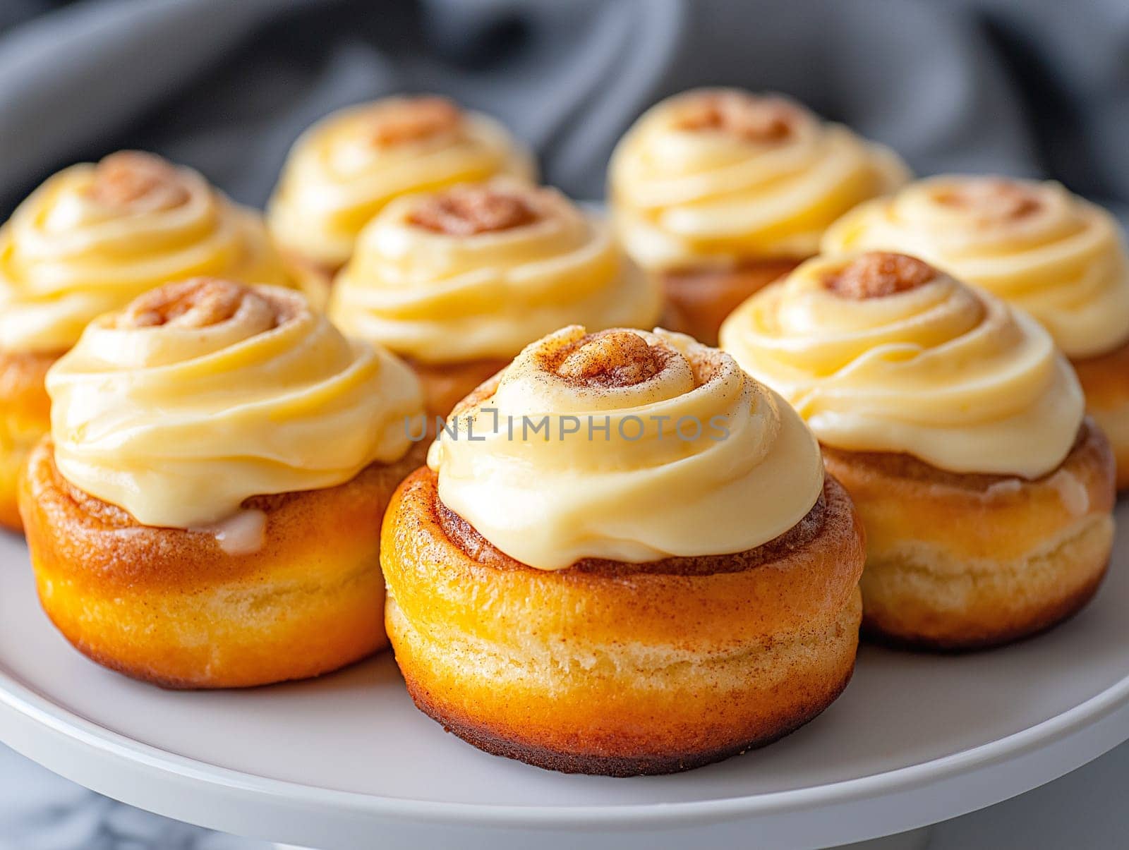 A plate of cinnamon rolls with icing on top. The rolls are arranged in a neat row and are all the same size