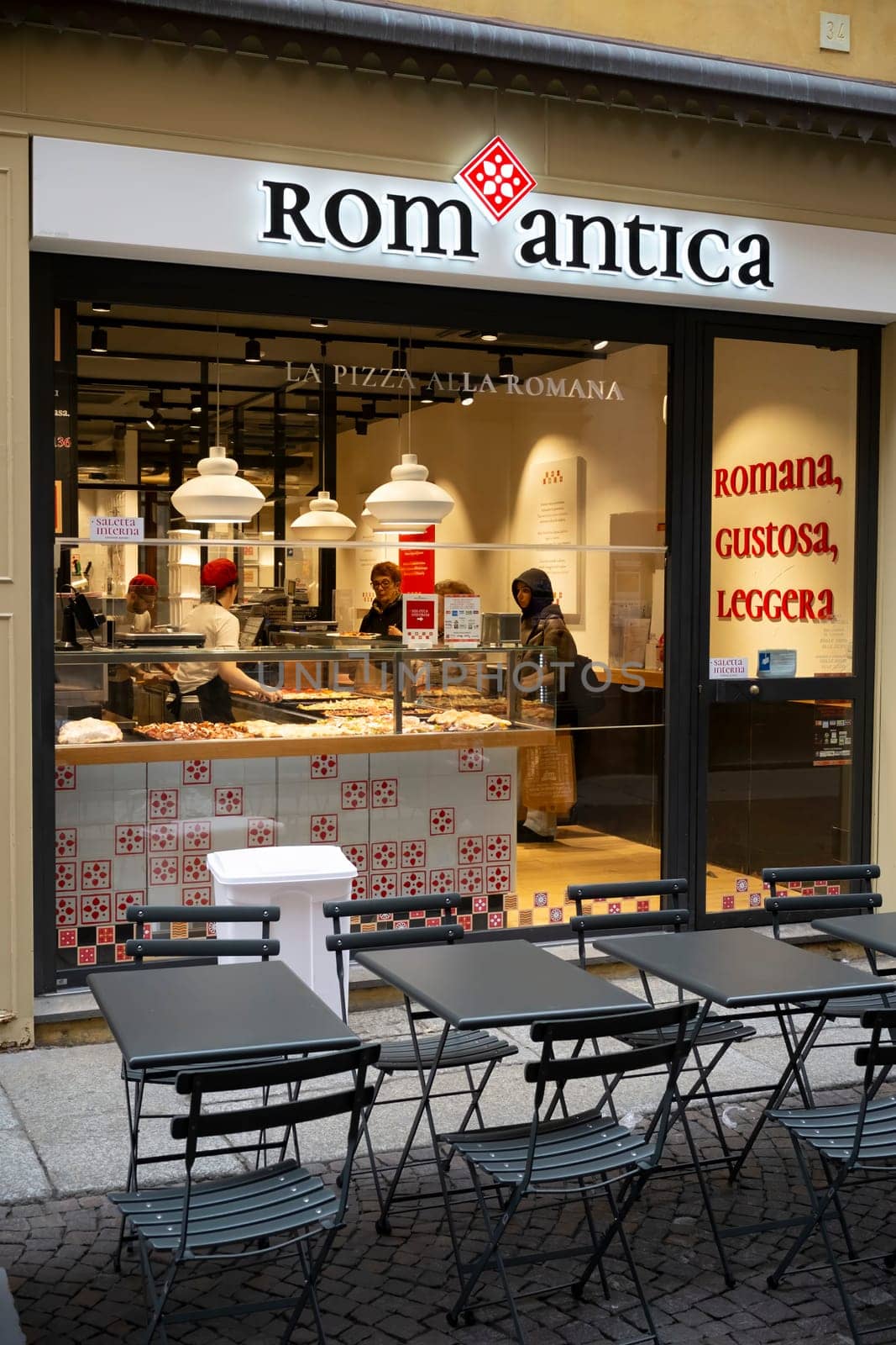 Cremona, Italy - November 20th 2024 Chefs preparing pizza alla romana inside rom antica pizzeria in cremona, italy, with outdoor tables and chairs