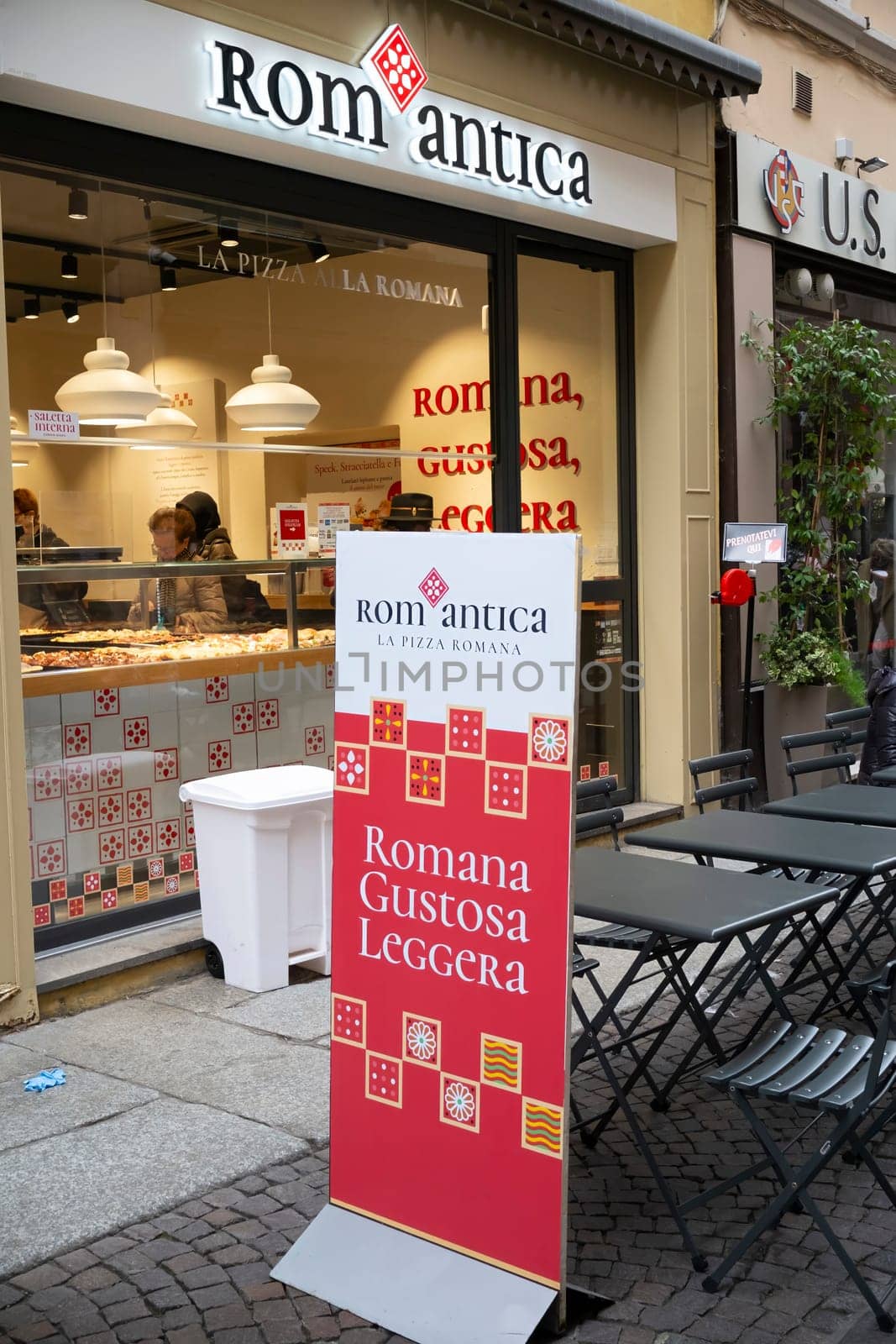 Cremona, Italy - November 20th 2024 Pizzeria romantica in cremona, italy, showcasing its roman-style pizza through a vibrant outdoor advertisement and storefront display
