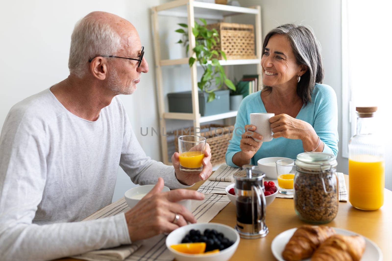 Married mature couple eating breakfast together at home. Man and woman looking at each other smiling.Lifestyle concept.