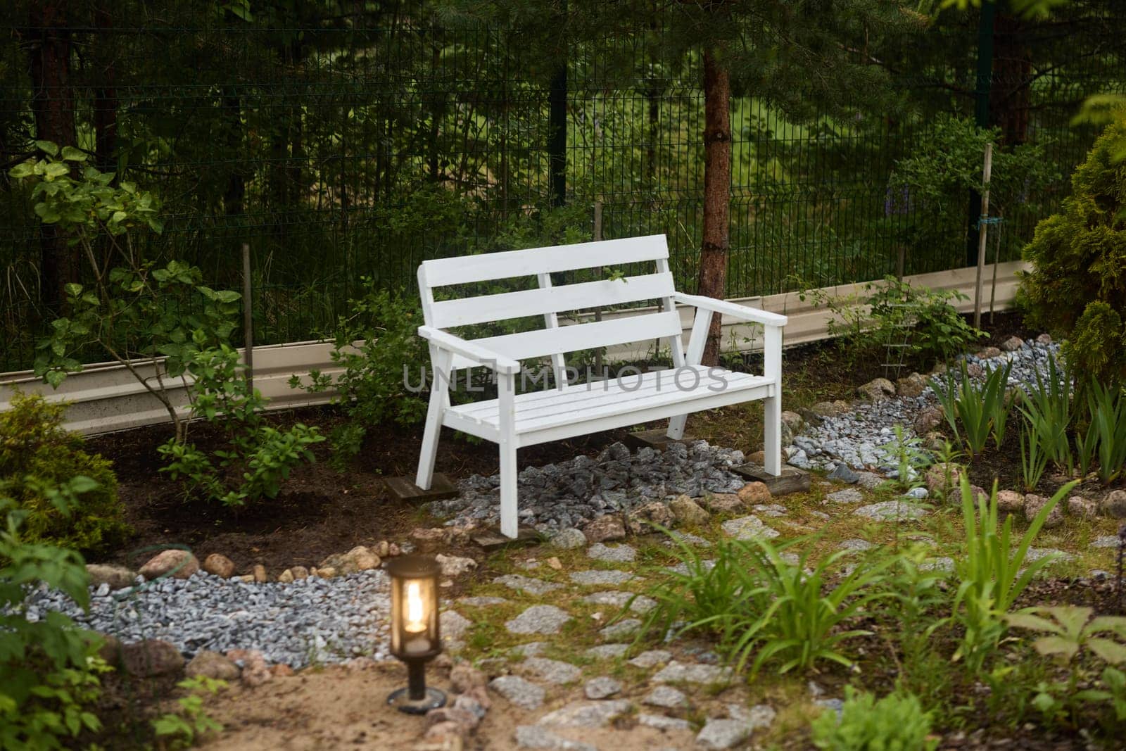 A beautifully tranquil white bench nestled in a lush garden, ideal for relaxation and outdoor enjoyment with nature
