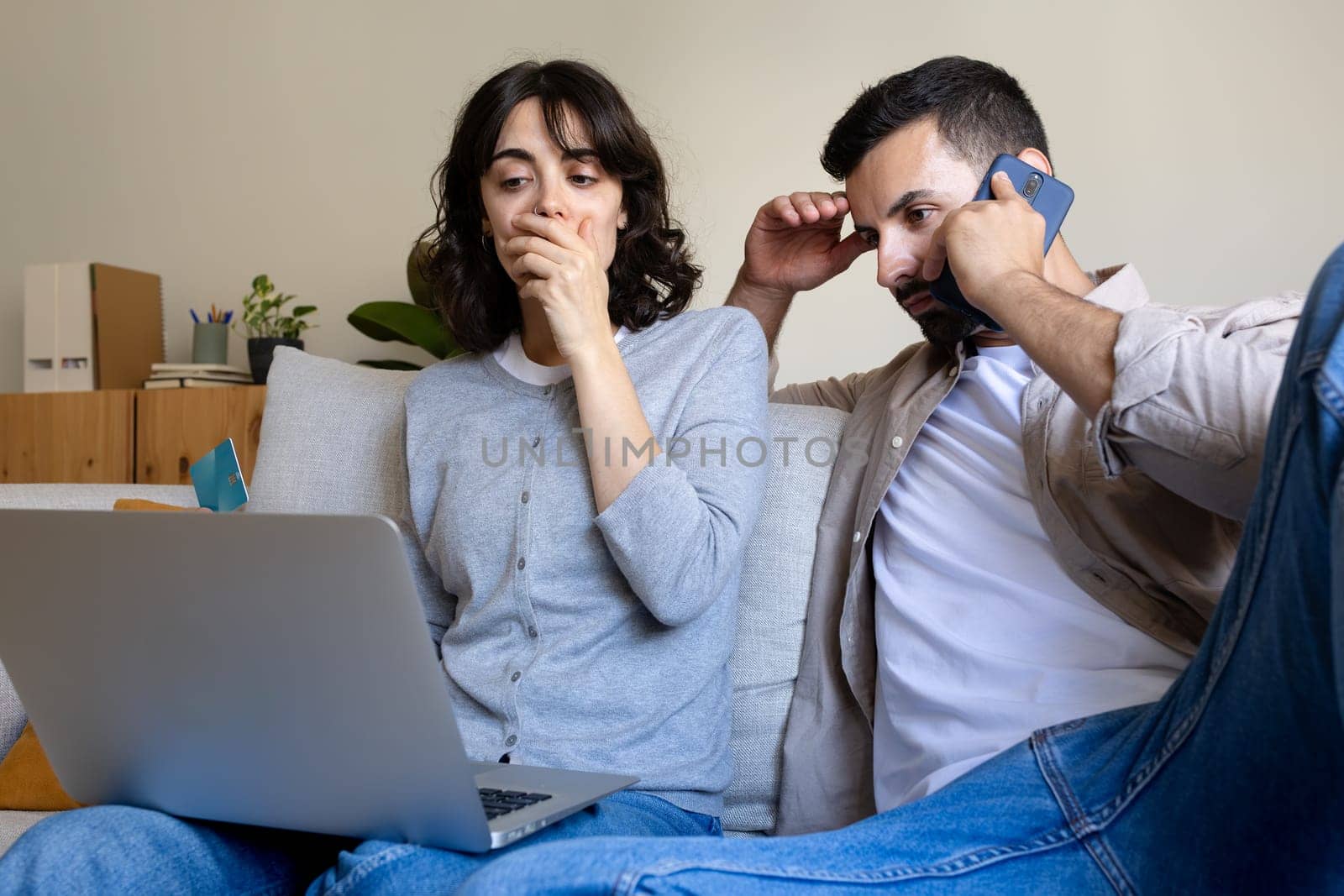 Caucasian couple having financial problems calling bank. Victims of fraud. Worried female holding credit card. Lifestyle.