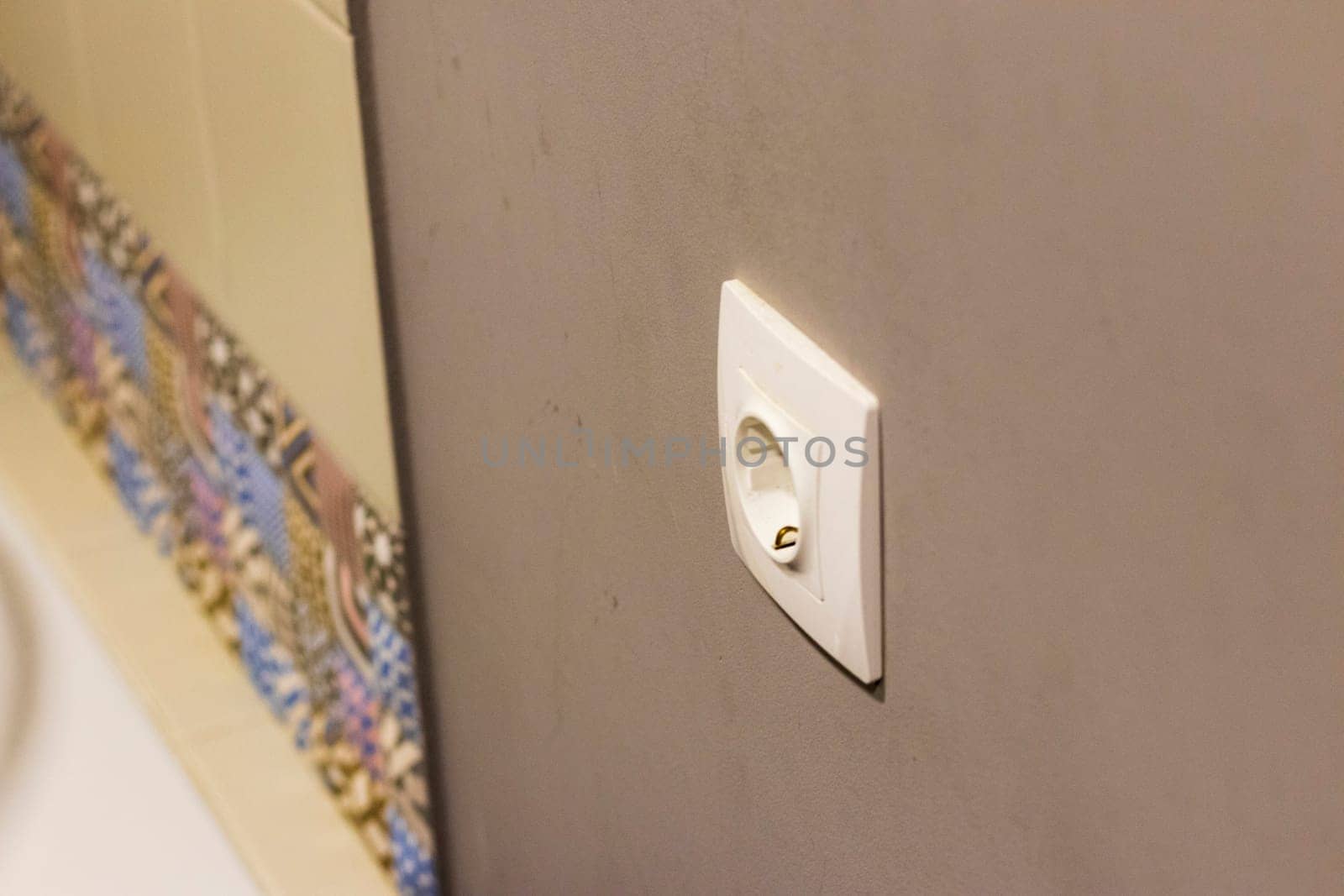 Shot of the decorative tiles and electrical socket in the bathroom