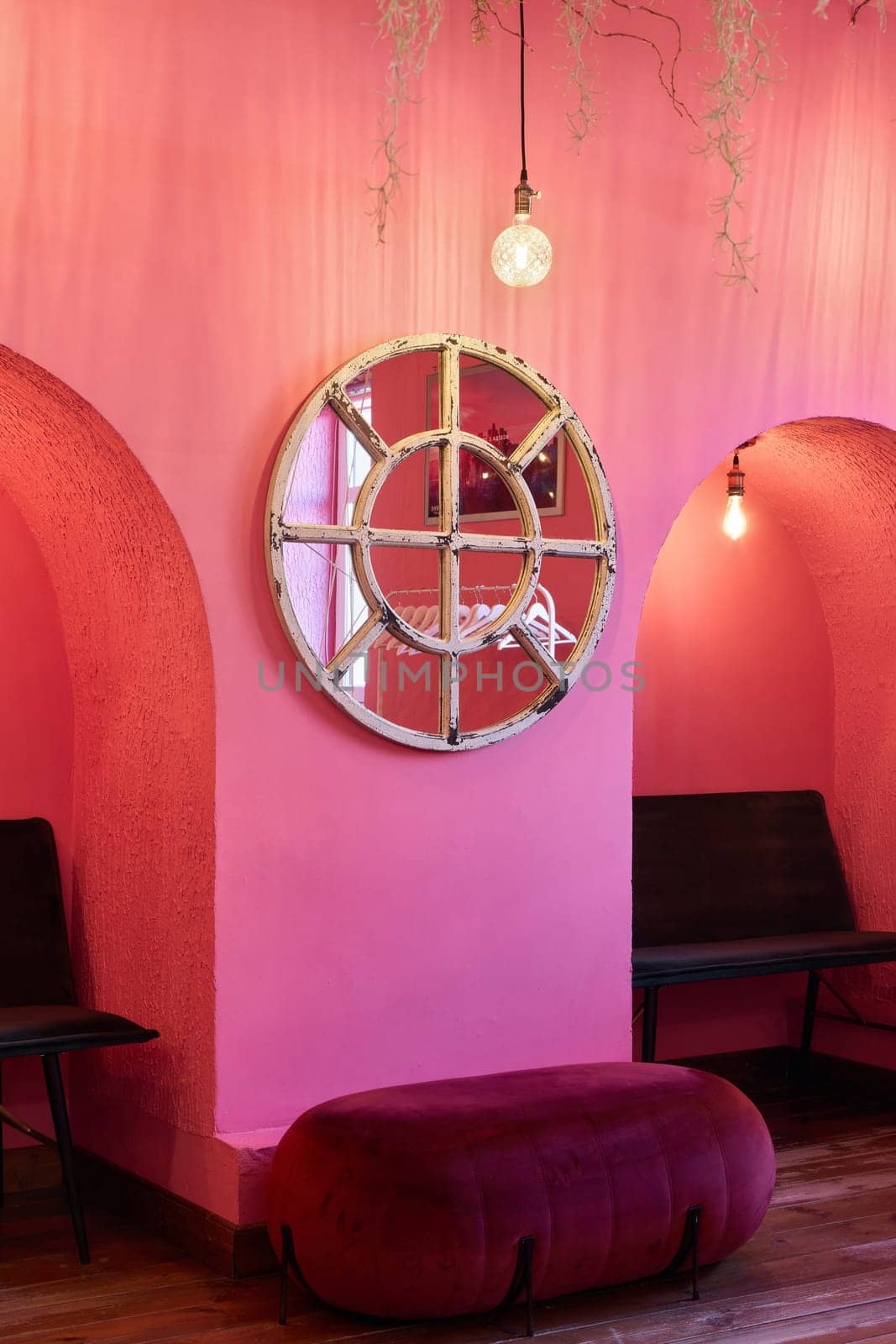 A stylish pink interior showcasing beautiful arches, a round mirror, and inviting cozy seating for relaxation