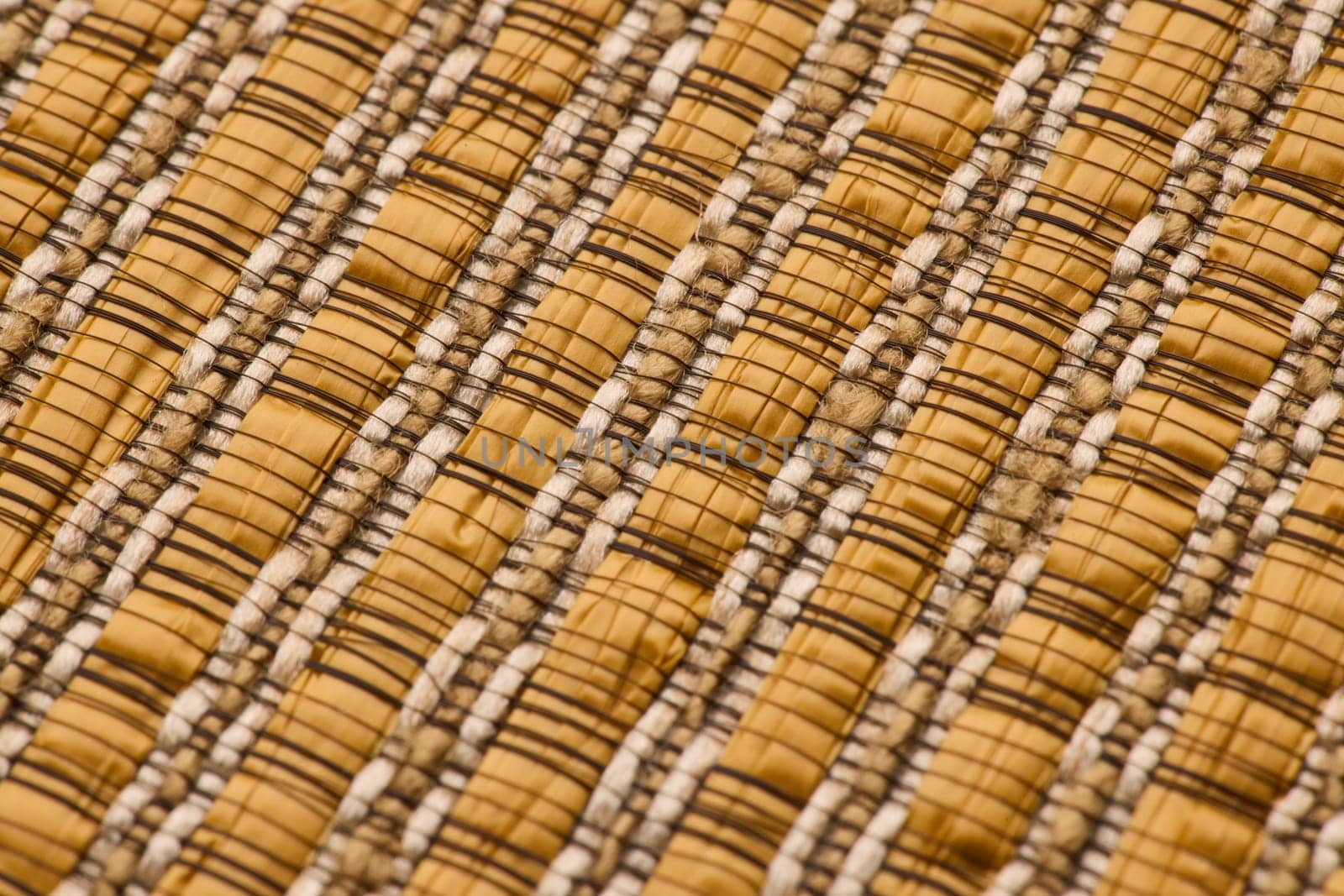A closeup view of woven fabric that showcases a blend of warm beige and rich brown textures and intricate patterns