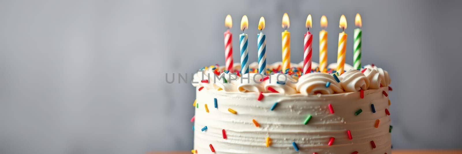 A festive birthday cake adorned with colorful sprinkles sits on a table, topped with eight lit candles. It represents celebration and joy during a special event.