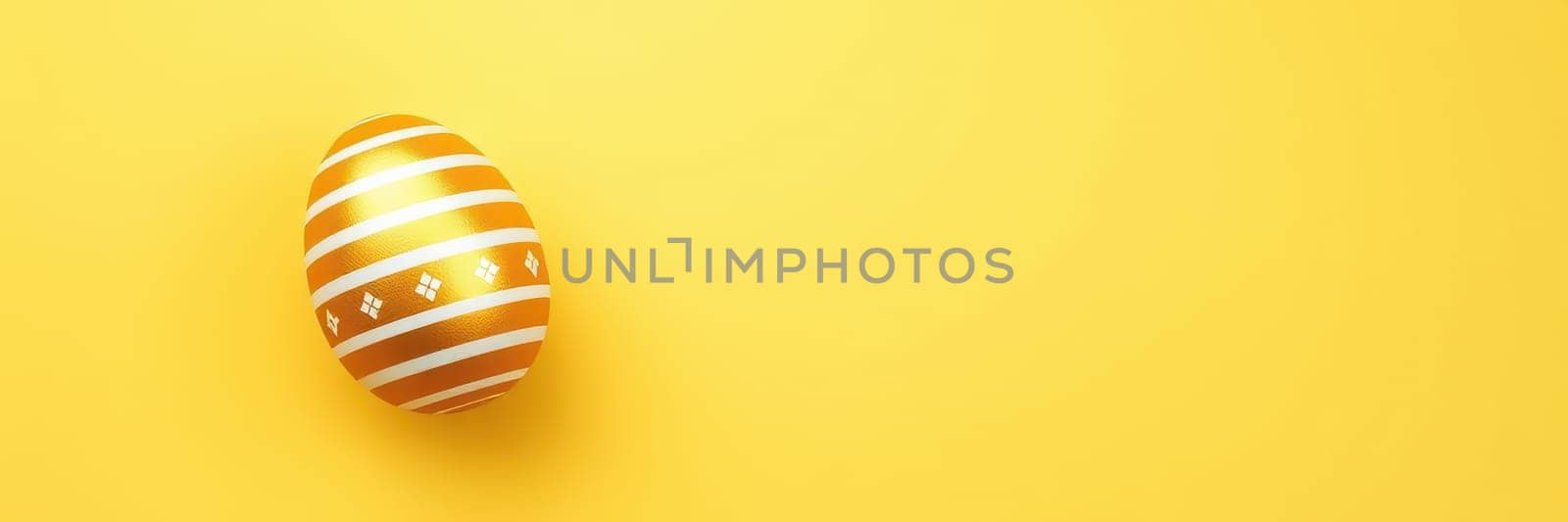 A beautifully decorated golden egg with white stripes rests on a vibrant yellow backdrop. This festive display captures the spirit of Easter and spring celebrations.
