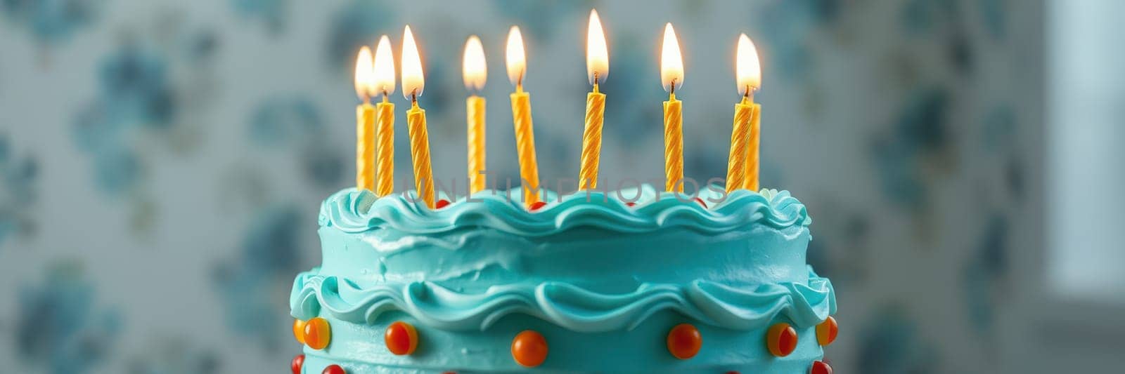 A delightful birthday cake adorned with blue frosting and bright candles is displayed on a table, surrounded by a cheerful atmosphere perfect for a festive celebration.